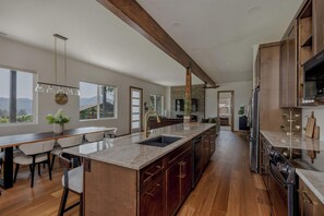 A modern kitchen with a large island, wooden cabinetry, and a stone backsplash. - Summers Hill - Newly Built Wine Country Estate (Carlton)