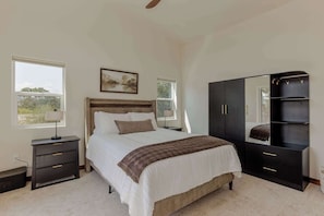 Quarto com cama, mesas de cabeceira, guarda-roupa e um quadro na parede.