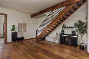 Ein geräumiger Raum mit einer Holztreppe, einem Sofa, einem Couchtisch und einem Kamin.