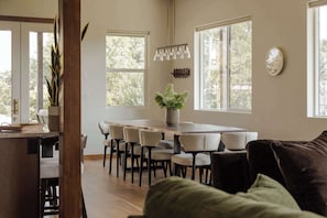 A dining area with a long table and multiple chairs, a vase with flowers, and a clock on the wall. - Summers Hill - Newly Built Wine Country Estate (Carlton)