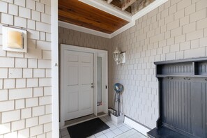 A clean, modern entrance with a white door, a black doormat, a white tiled floor, a grey fireplace, and a wall-mounted globe. - Waterfront Slice of WB Paradise w Dock and Boat Lift! PRIME location! (Wrightsville Beach)