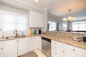 A modern kitchen with white cabinetry, granite countertops, and a dishwasher. - Waterfront Slice of WB Paradise w Dock and Boat Lift! PRIME location! (Wrightsville Beach)
