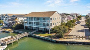 A waterfront property with a two-story building, dock, and a street view. - Waterfront Slice of WB Paradise w Dock and Boat Lift! PRIME location! (Wrightsville Beach)