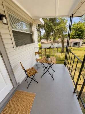 A covered porch with two wooden chairs and a table, a small rug, and a potted plant. - Terrific 2-bedroom apartment with AC in sunny Tampa (Tampa)