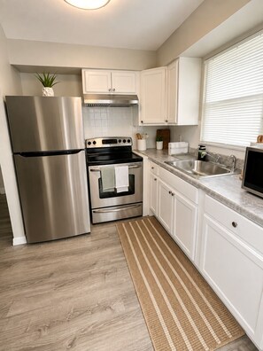 A modern kitchen with stainless steel appliances, white cabinetry, and a wooden floor. - Terrific 2-bedroom apartment with AC in sunny Tampa (Tampa)