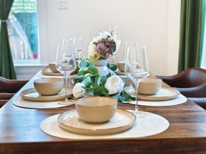 A dining table set with bowls, wine glasses, and a centerpiece of flowers. - Spacious 4-bedroom house in quaint Houston with AC and gym access (Houston)