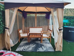 A covered outdoor seating area with a table and chairs, surrounded by a semi-transparent canopy. - Spacious 4-bedroom house in quaint Houston with AC and gym access (Houston)