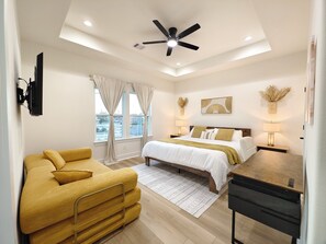 A modern bedroom with a bed, a sofa, a desk, and a ceiling fan. - Spacious 4-bedroom house in quaint Houston with AC and gym access (Houston)