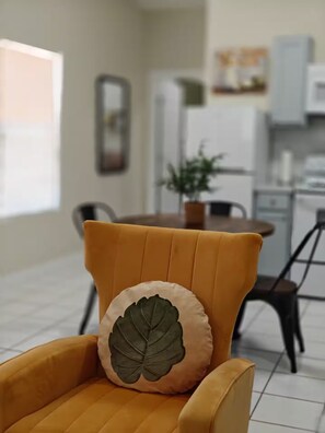 A yellow armchair with a leaf-shaped pillow in a modern kitchen with a dining table and chairs. - Bugambilias Apartment (Laredo)
