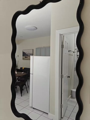 A kitchen with a white refrigerator, a dining area with a table and chairs, and a door leading to another room. - Bugambilias Apartment (Laredo)
