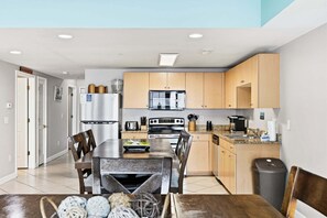 A modern kitchen with a central island, wooden cabinets, and stainless steel appliances. - Six on the Beach - Spacious 6BR Condo w/ Shared Pool and Hot Tub (Sleeps 12) (North Myrtle Beach)