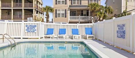 A swimming pool with a no diving allowed sign, a no lifeguard on duty sign, and shallow water warning.