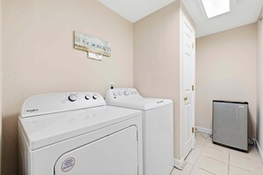 Une buanderie équipée de deux lave-linge Whirlpool et d’un réfrigérateur.