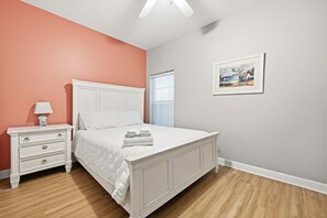 A bedroom with a bed, a nightstand, a lamp, and a painting on the wall. - Six on the Beach - Spacious 6BR Condo w/ Shared Pool and Hot Tub (Sleeps 12) (North Myrtle Beach)
