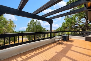 A wooden deck with a railing, a table, and a bench.