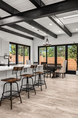 A modern kitchen with a bar area, large windows, and a view of the outdoors.