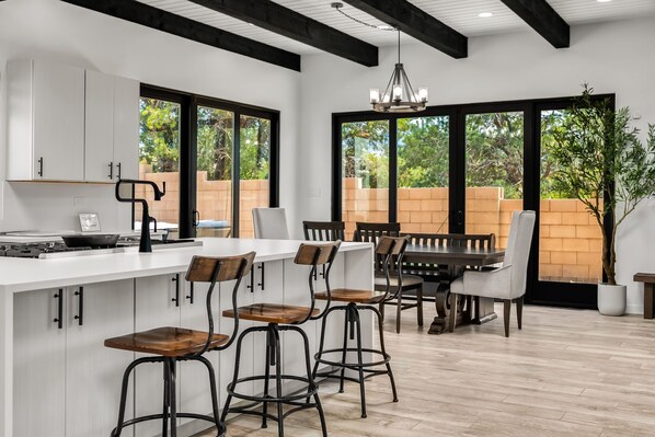 A modern kitchen with a large island, bar stools, and a dining table with chairs.