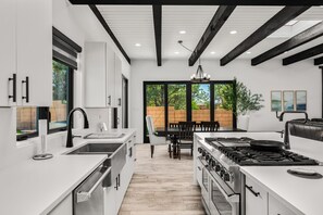 A modern kitchen with white cabinetry, a gas stove, and a dining area with a table and chairs.