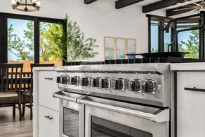 A kitchen with a stainless steel stove, oven, and a dining area with a table and chairs.
