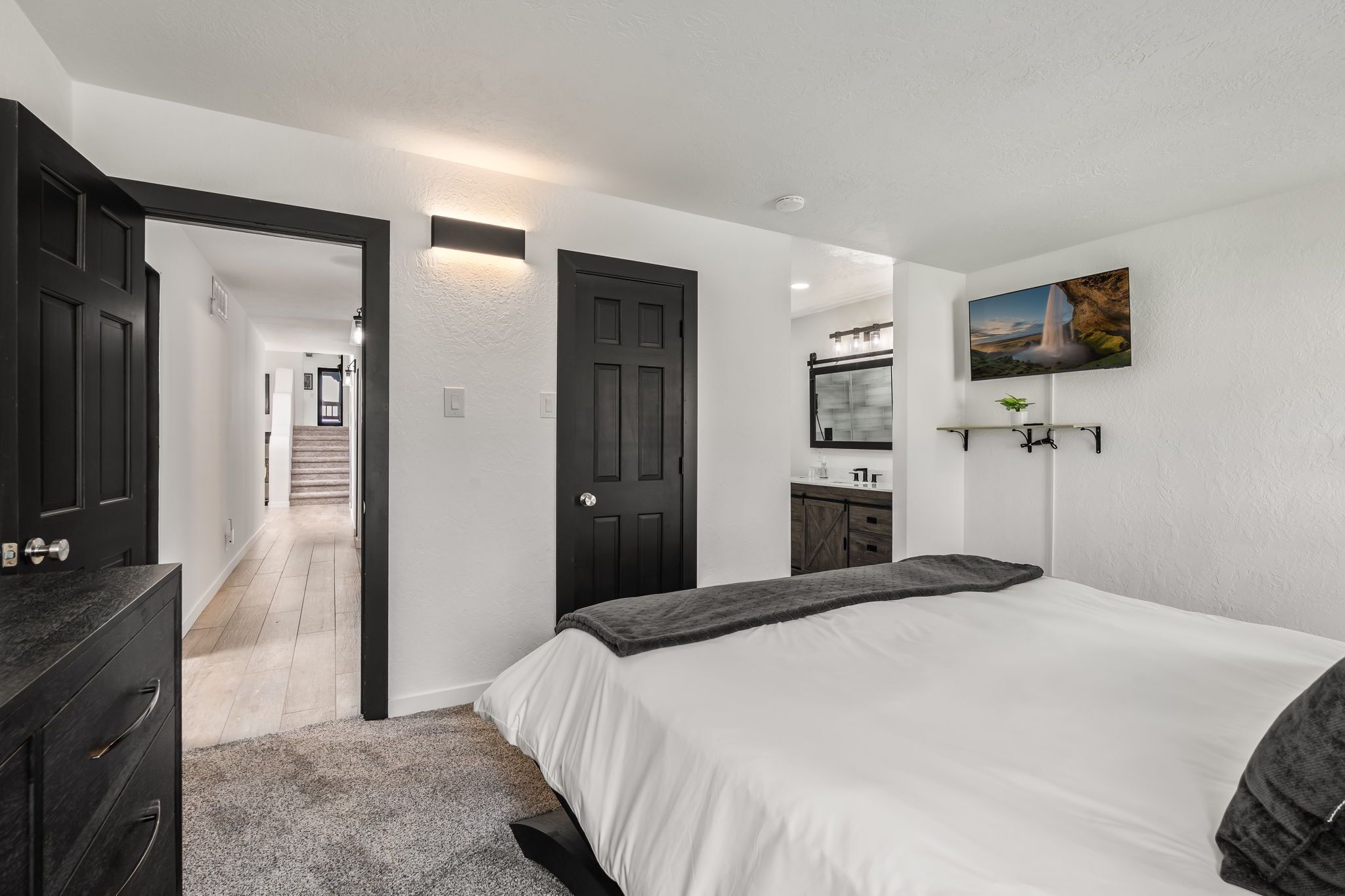 Un dormitorio con cama, cómoda y un pasillo que conduce a una escalera.