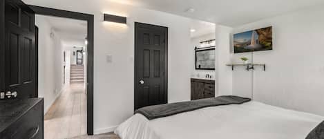 Un dormitorio con cama, cómoda y un pasillo que conduce a una escalera.