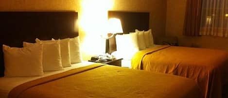 Une chambre d’hôtel avec deux lits, une table de chevet et une lampe.