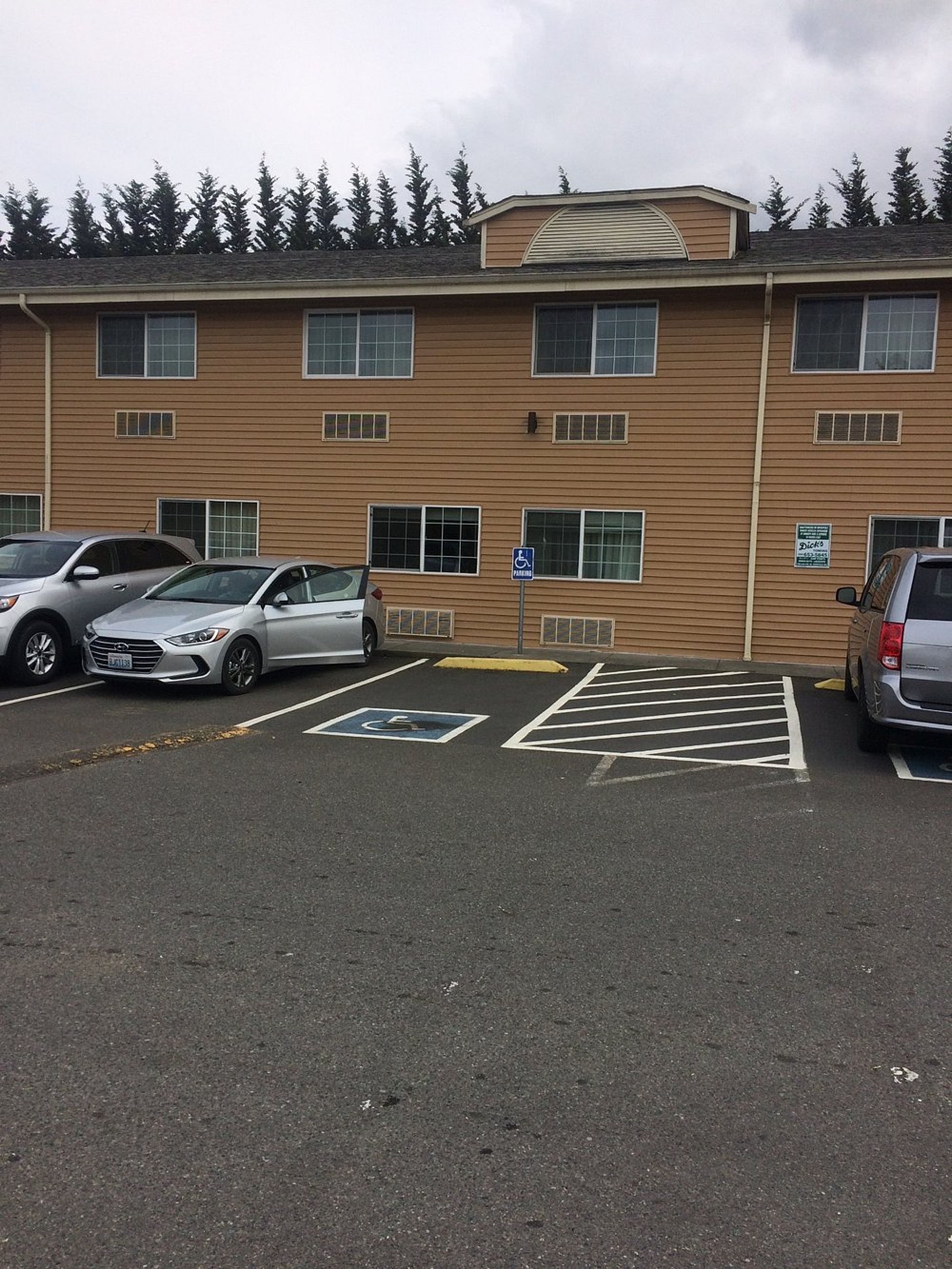 A parking lot with marked disabled parking spaces and a building with multiple windows and a flat roof.