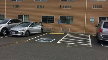 A parking lot with marked disabled parking spaces and a building with multiple windows and a flat roof.