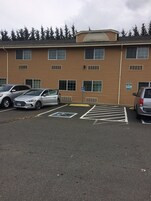 Un estacionamiento con espacios reservados para personas con discapacidad y un edificio con varias ventanas y techo plano.