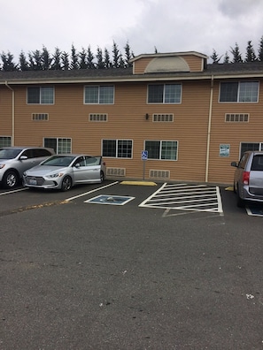 A parking lot with marked disabled parking spaces and a building with multiple windows and a flat roof.