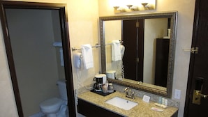 Baño con inodoro, lavamanos, espejo y zona de ducha.