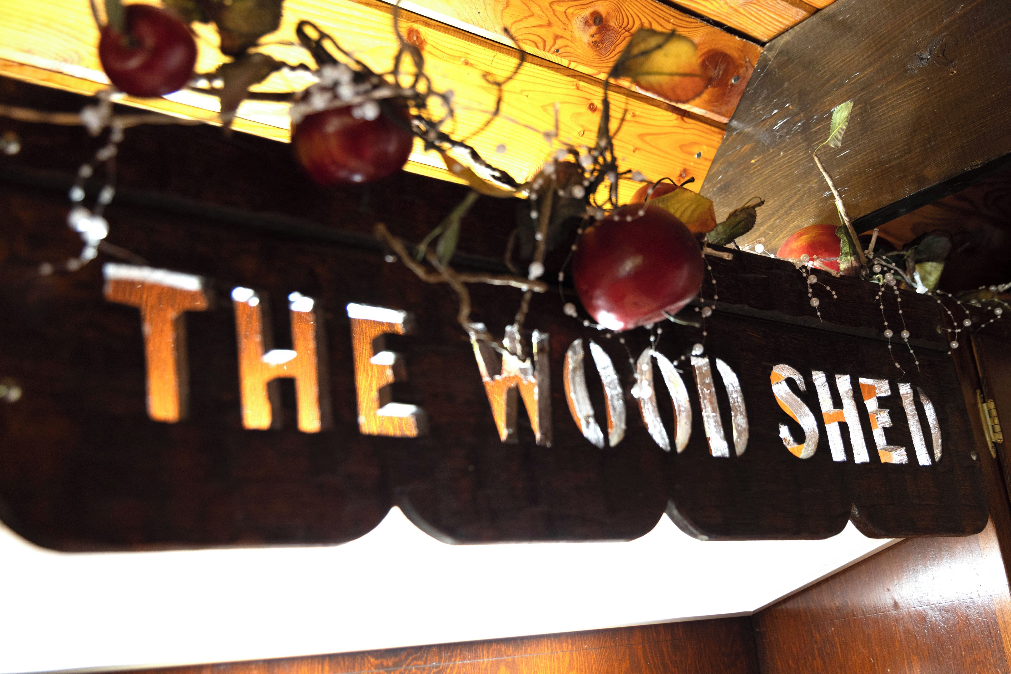 A wooden sign with the text 'THE WOOD SHELL' and decorative elements like fruits and vines.