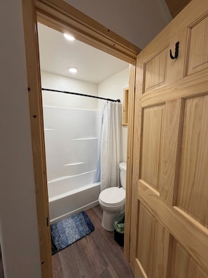 Un baño con bañera, inodoro y puerta de madera.