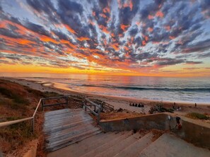A coastal scene with a wooden staircase leading down to a sandy beach, overlooking the ocean. - Ocean-View 3-Bed House in Halls Head (Halls Head)