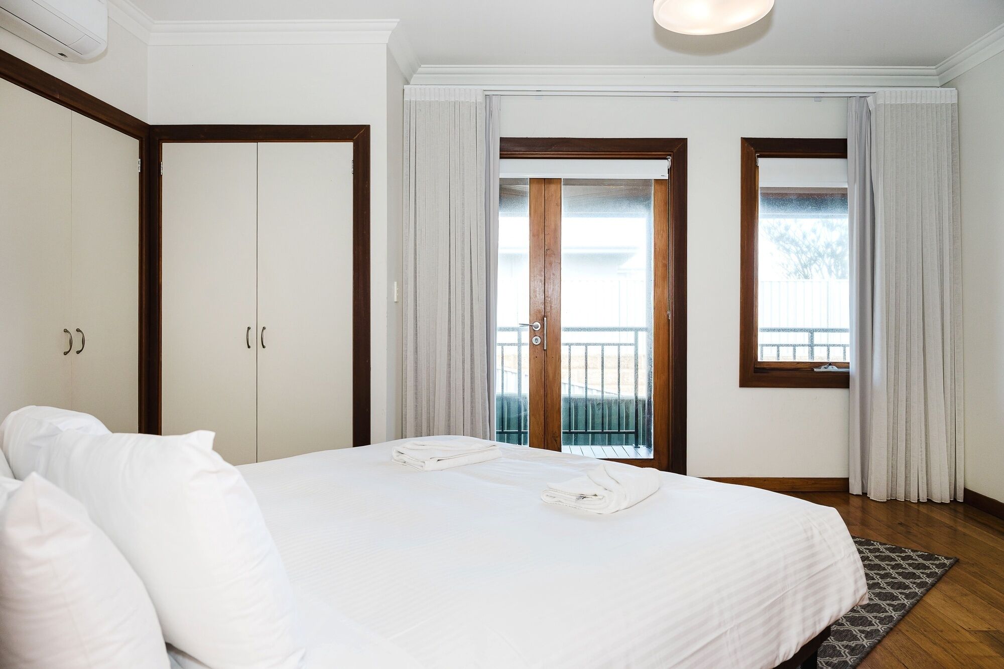 Ett hotellrum med en säng, en garderob, en balkong med utsikt och ett fönster med gardiner.