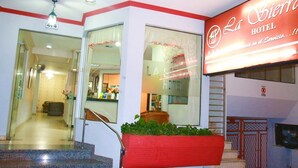 Entrada de un hotel con una recepción, una escalera y un letrero que dice 'La Sierra Hotel'.