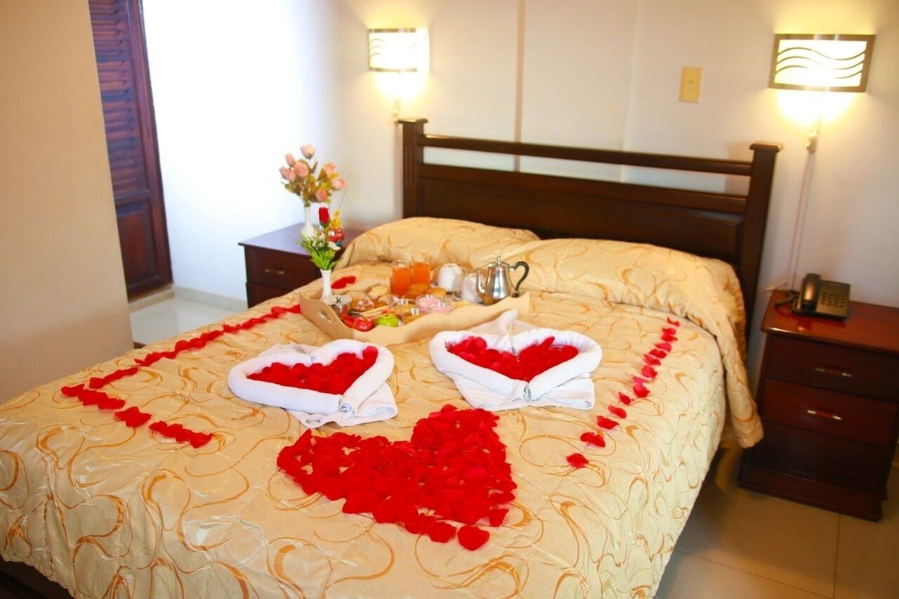 A hotel room with a bed, a bedside table with a lamp, and a nightstand with a phone.