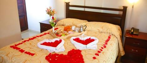 A hotel room with a bed, a bedside table with a lamp, and a nightstand with a phone.