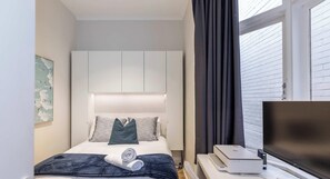 Une chambre d’hôtel équipée d’un lit, d’un téléviseur à écran plat, d’une imprimante et d’une fenêtre avec des rideaux.