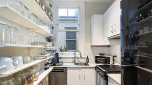A compact kitchen with white cabinets, a built-in oven, a microwave, and a sink. - Quiet Art Deco 2BR Retreat in the Heart of Potts Point (Potts Point)
