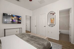 A bedroom with a bed, a TV mounted on the wall, a door, and a bathroom visible through an open door. - Urban Oasis in Downtown Austin (Austin)