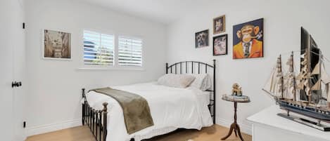 Un dormitorio con una cama, una mesita con un modelo de barco y decoración en la pared.