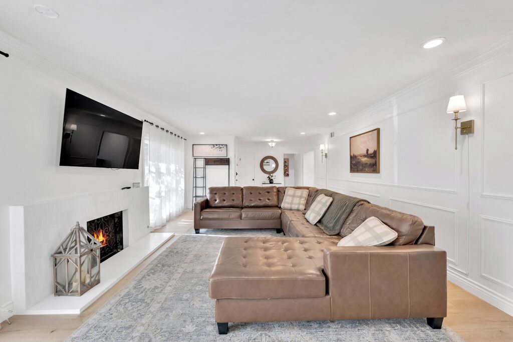 A modern living room with a sectional sofa, a fireplace, and a flat-screen TV mounted on the wall.