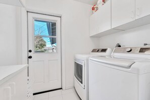 A laundry room with a white door, two washing machines, and a cabinet above.