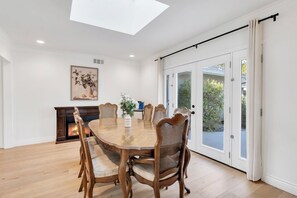 A dining room with a large wooden table, surrounded by chairs, a fireplace, and a view through glass doors. - 4BR Family Getaway  Private Office, Playground & Backyard (Thousand Oaks)