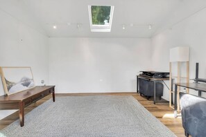 A spacious room with a skylight, a desk, a chair, and a rug.