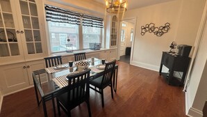 A dining area with a glass table, black chairs, and a chandelier.