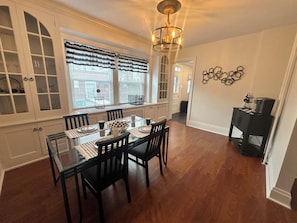 A dining area with a glass table, black chairs, and a chandelier.