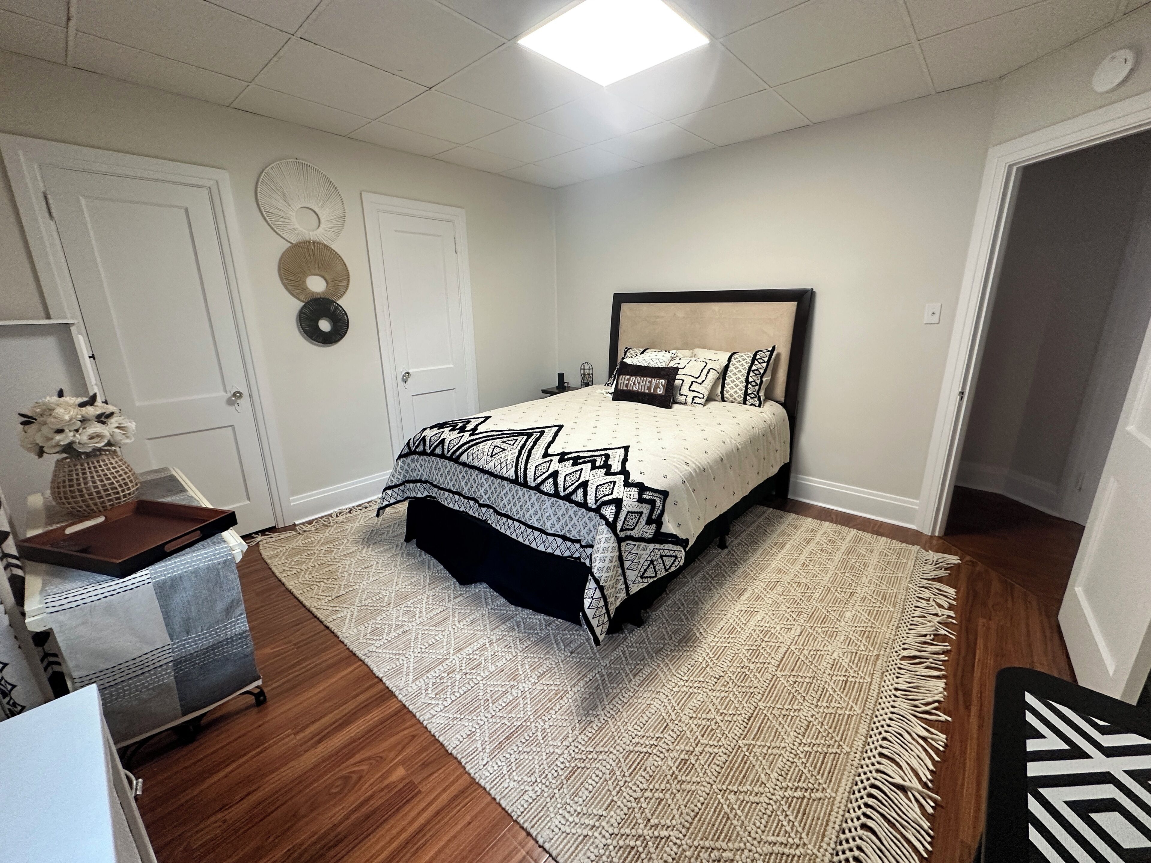 A bedroom with a bed, a bedside table, a rug, and a door.