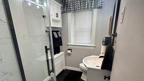 A bathroom with a glass shower enclosure, a white sink, and a toilet. - Hershey Station at the Square No. 1 - Closest Rental to Downtown Square Hershey (Hershey)